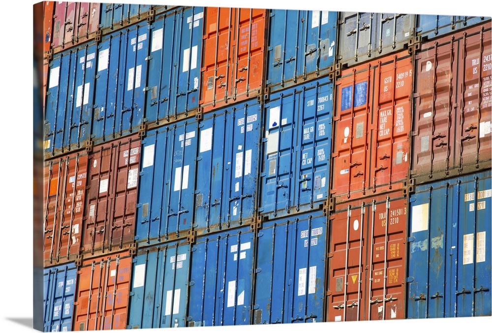 A stack of cargo containers, commercial freight containers, packed together and waiting to be moved.