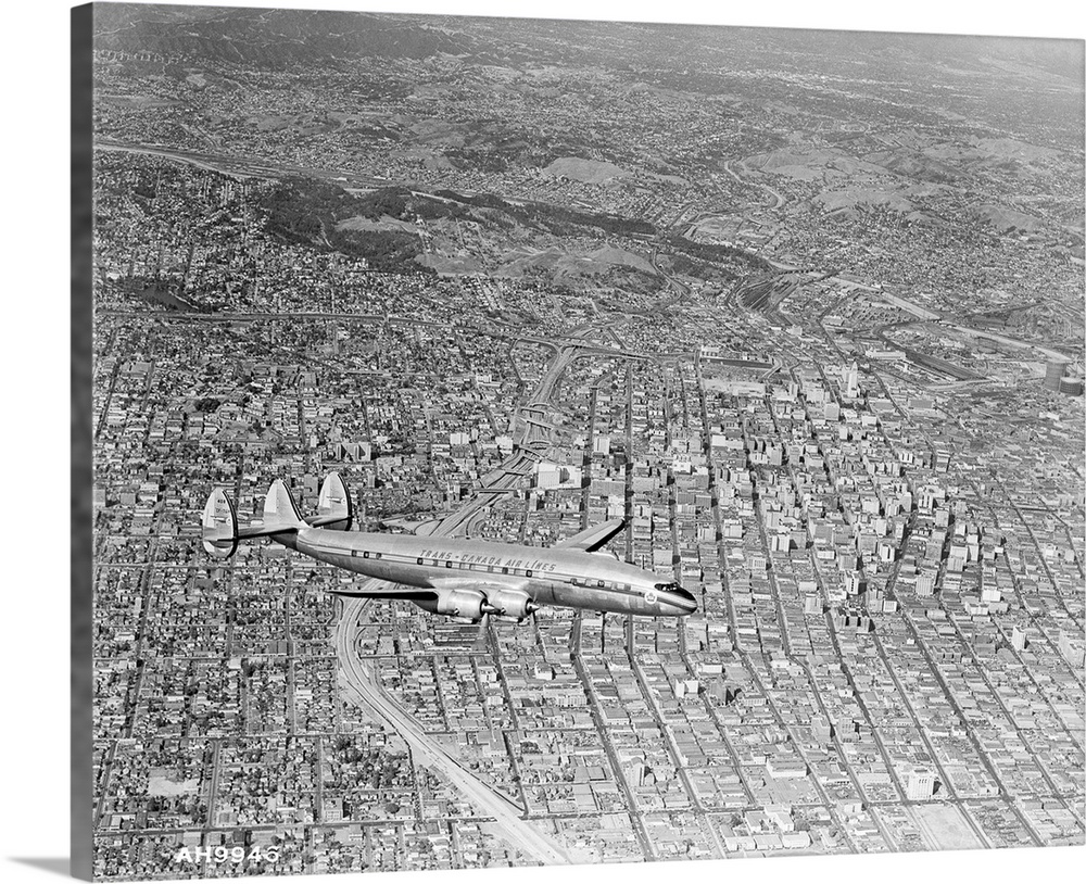 A Super Constellation flying over downtown Los Angeles. The ribbon like roadway directly beneath the plane is the city's n...