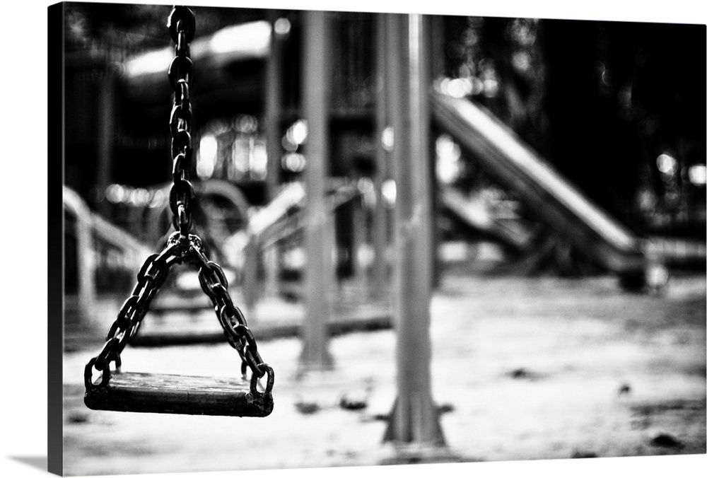 A swing on an empty playground, in monochrome