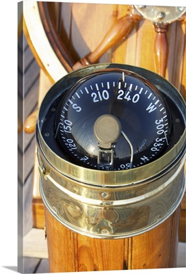 A warm glow highlights the ship's wheel and compass on a classic sailing yacht