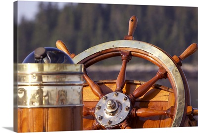 A warm glow highlights the ship's wheel and compass on a classic sailing yacht