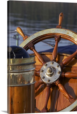 A warm glow highlights the ship's wheel and compass on a classic sailing yacht