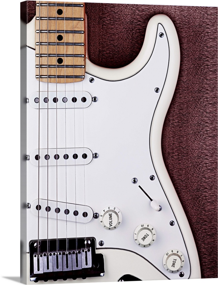 A white electric guitar on a wooden surface
