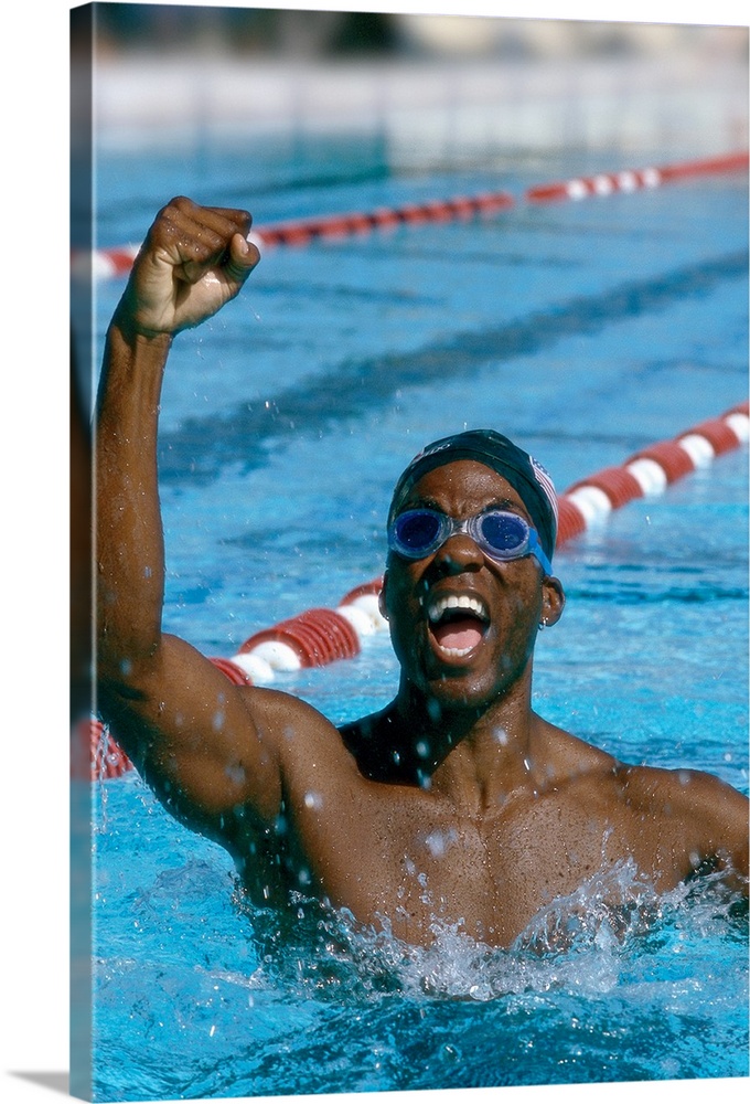 portrait of a young male swimmer raising his hands in victory
