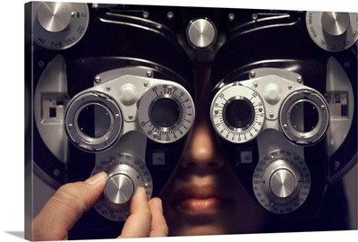 A young woman sits and has her eyes checked