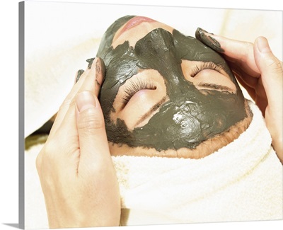 Aesthetician Rubbing Mud Pack on Woman's Face