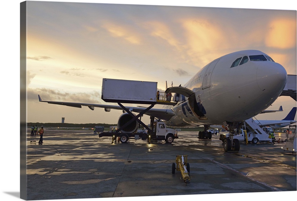 Airplane on tarmac being unloaded after landing, at sunset, Punta Cana Airport, Dominican Republic