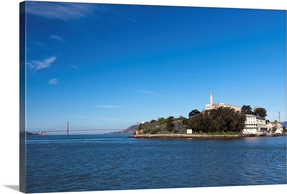 Alcatraz island and rock and Golden Gate bridge on bright and sunny day.