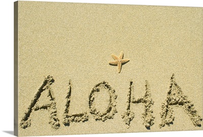 Aloha written in sand with small orange seastar above