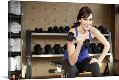 An active female lifting weights in a private gym.