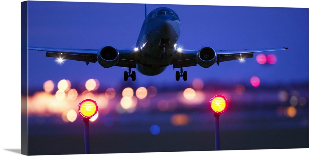 Composite close-up of an airplane landing with blurred lights of the airport in the background
