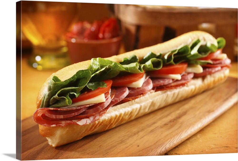 An Italian sub sandwich with ham,salami,pepperoni, Swiss cheese, lettuce and tomato on a sandwich roll.