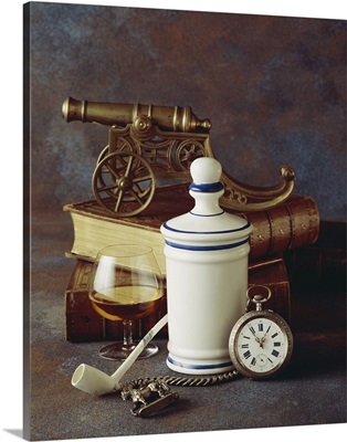Antique cannon on old books with wine glass and pipe, close-up