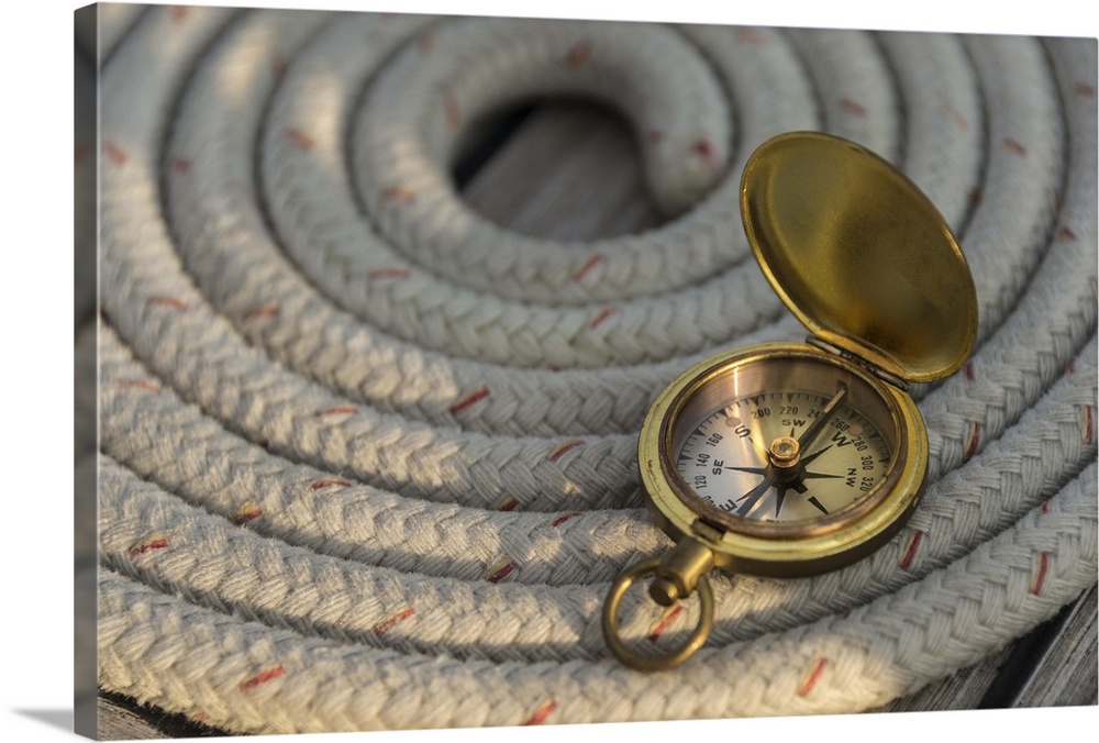 Antique compass on coiled rope on sailboat