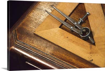 Antique set square and pair of compasses on wooden table