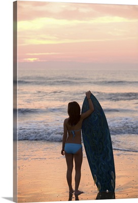 Asian girl holding surfboard at beach