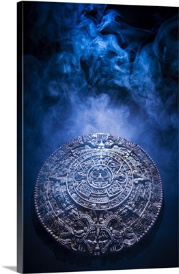Aztec calendar stone carving surrounded by smoke