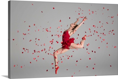 Ballerina jumping through red flowers petals