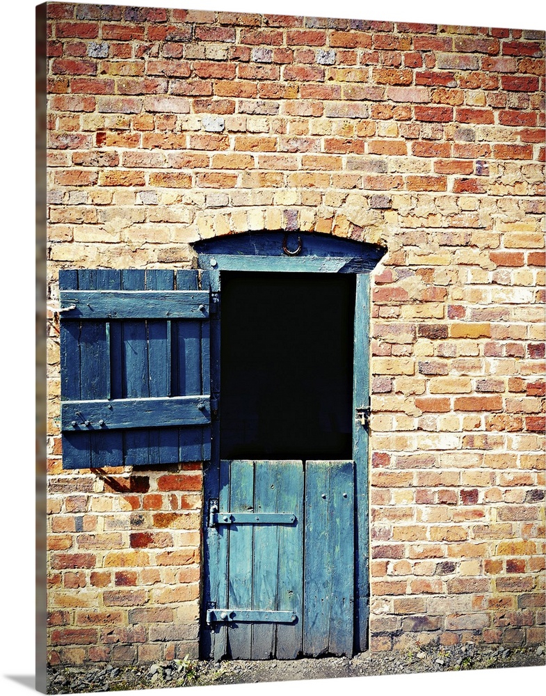 Blue barn door set in old brick wall.