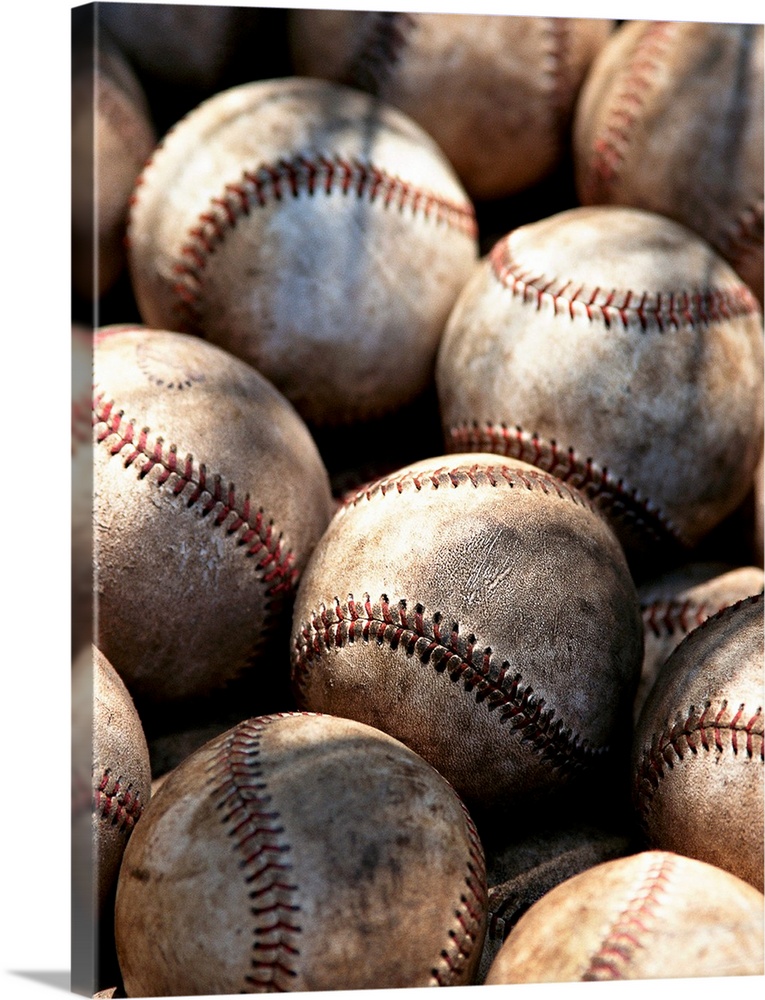 Up-close photograph of dirty baseballs with rays of light scattered on them.