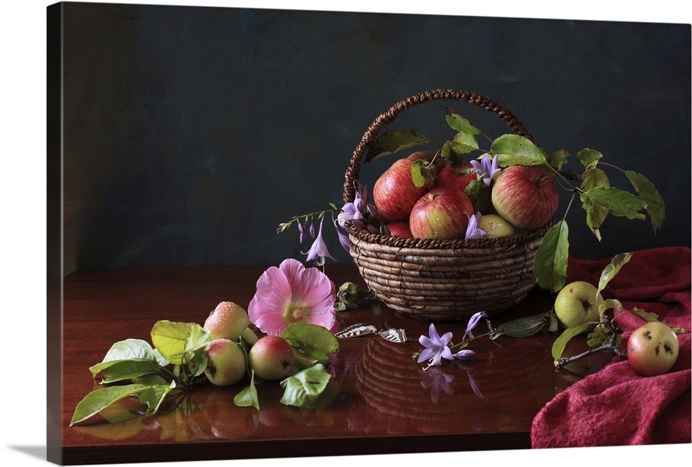 Basket of apples and blue flowers with reflection on table.