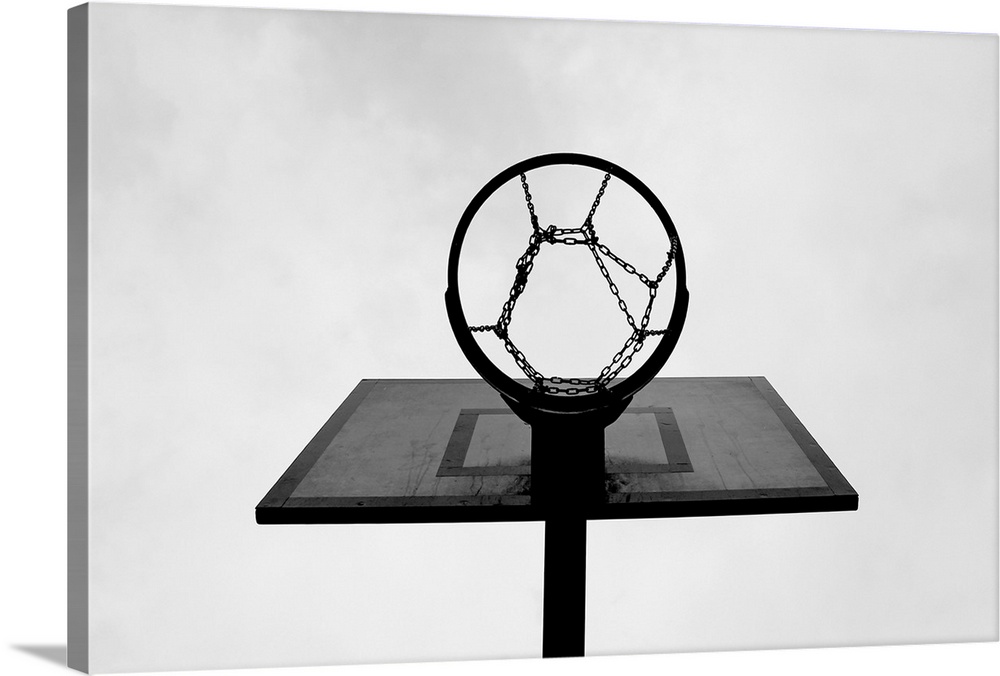 This is a monochromatic, horizontal photograph taken from below an outdoor basketball hoop.