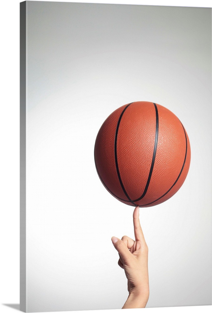 Basketball on index finger, hands close-up Solid-Faced Canvas Print