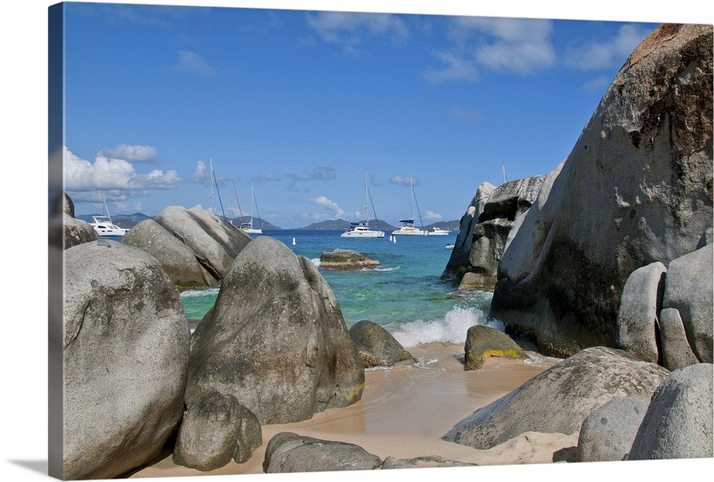 Baths of Virgin Gorda in  British Virgin Islands with boulders and moored sailboats in clear blue Caribbean Sea.