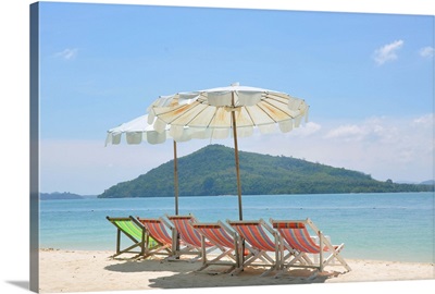 Beach chair and umbrella on beach and Rang Yai Island background.