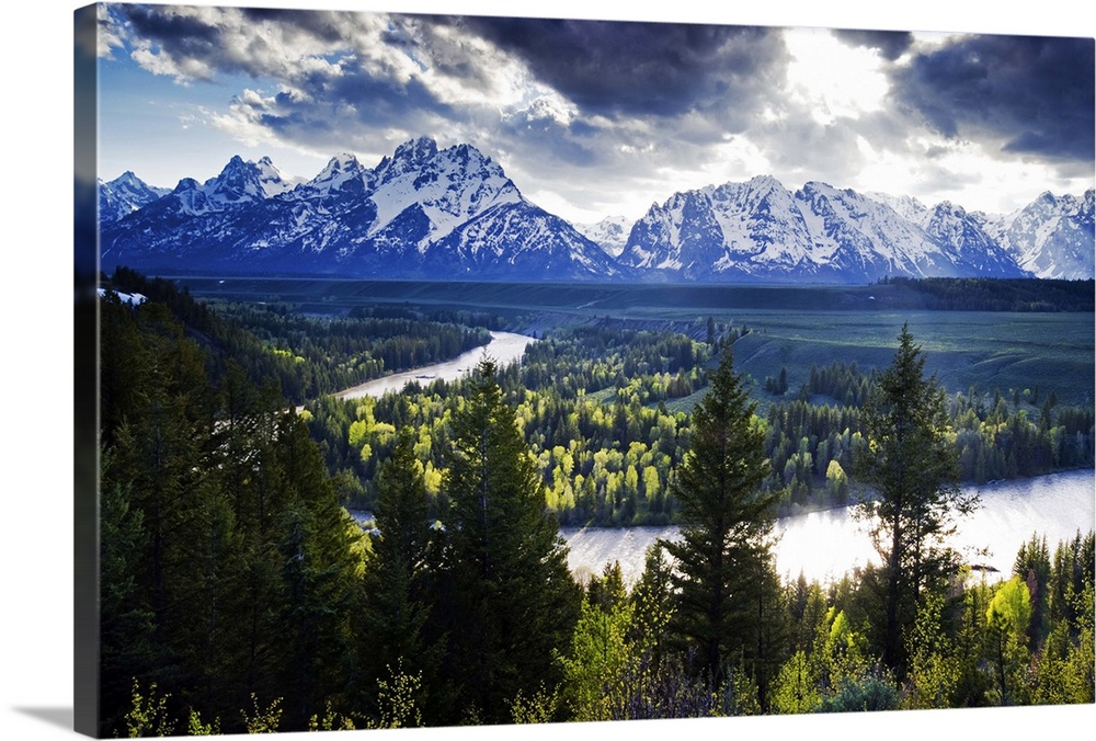 Beams of light penetrate the clouds at the classic Snake River Overlook in Grand Teton National Park, Wyoming.