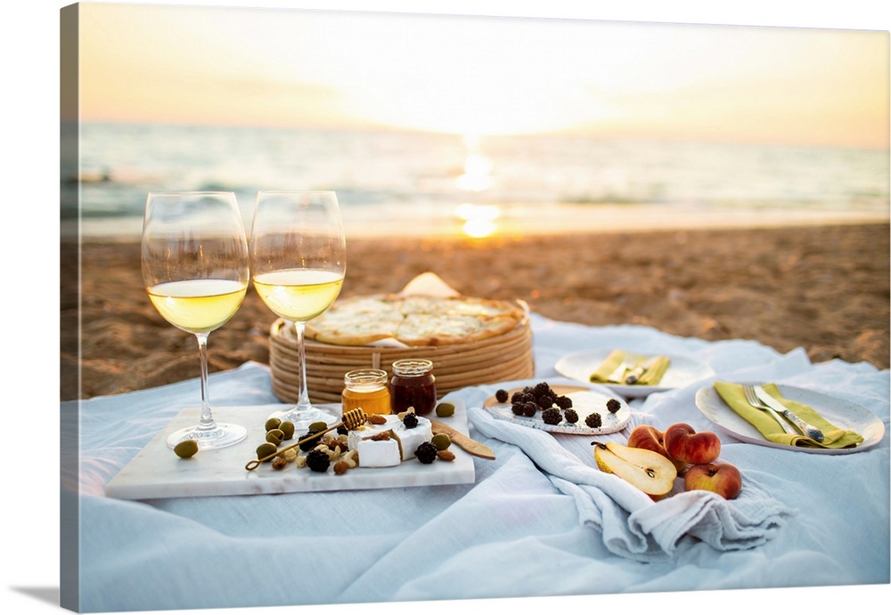 Beautiful served picnic at seaside on sunset. Romantic picnic for two with fruits, snacks, white wine and cheese pizza on ...
