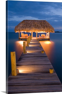 Belize, Placencia, pier with palapa illuminated at dusk