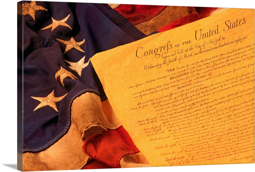 A piece of paper with the first ten amendments is laid over the 13 star American flag.