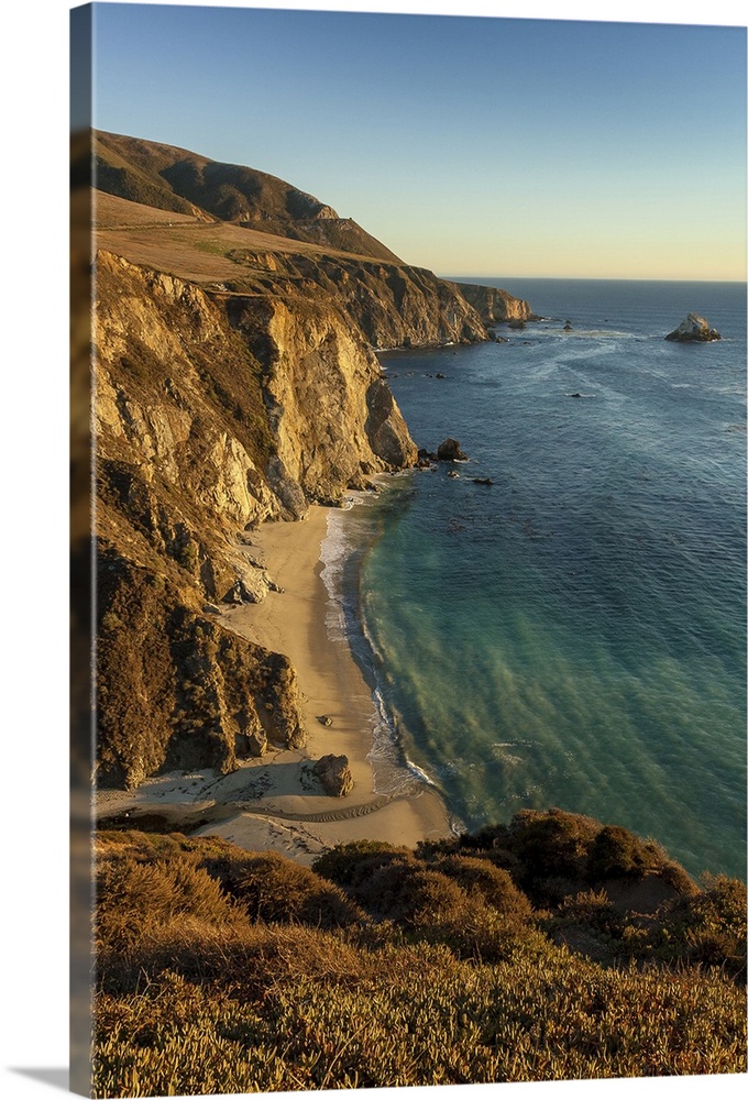 A view of Bixby Creek entering the Pacific Ocean on California's Big Sur coastline at sunset looking south.
