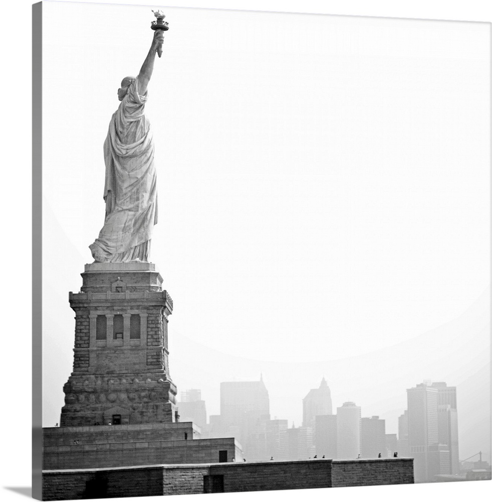 Black and white image of statue of Liberty with island of Manhattan/New York City in background.