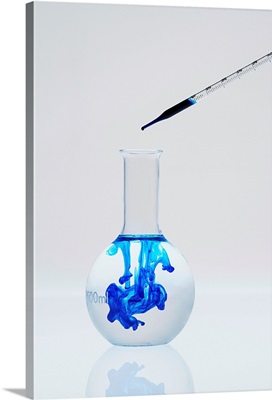 Blue liquid being dropped into a beaker of clear water
