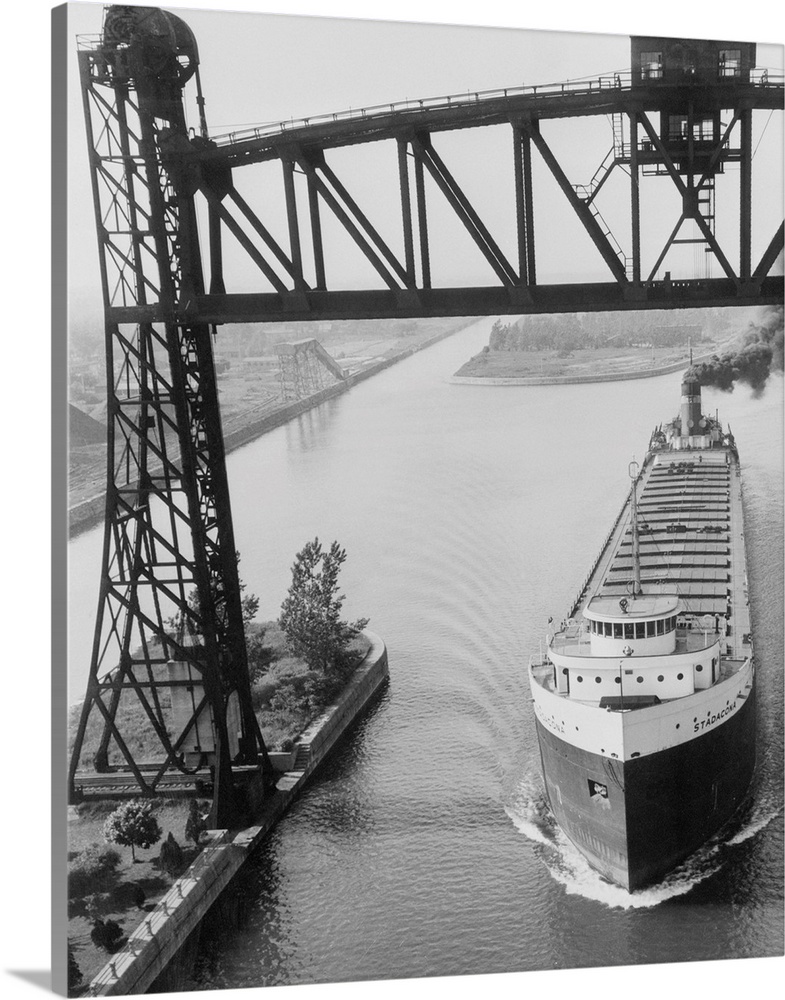 A grain boat passes under a huge railway lift bridge on the Welland Canal, which connects Lake Erie with Lake Ontario. Shi...