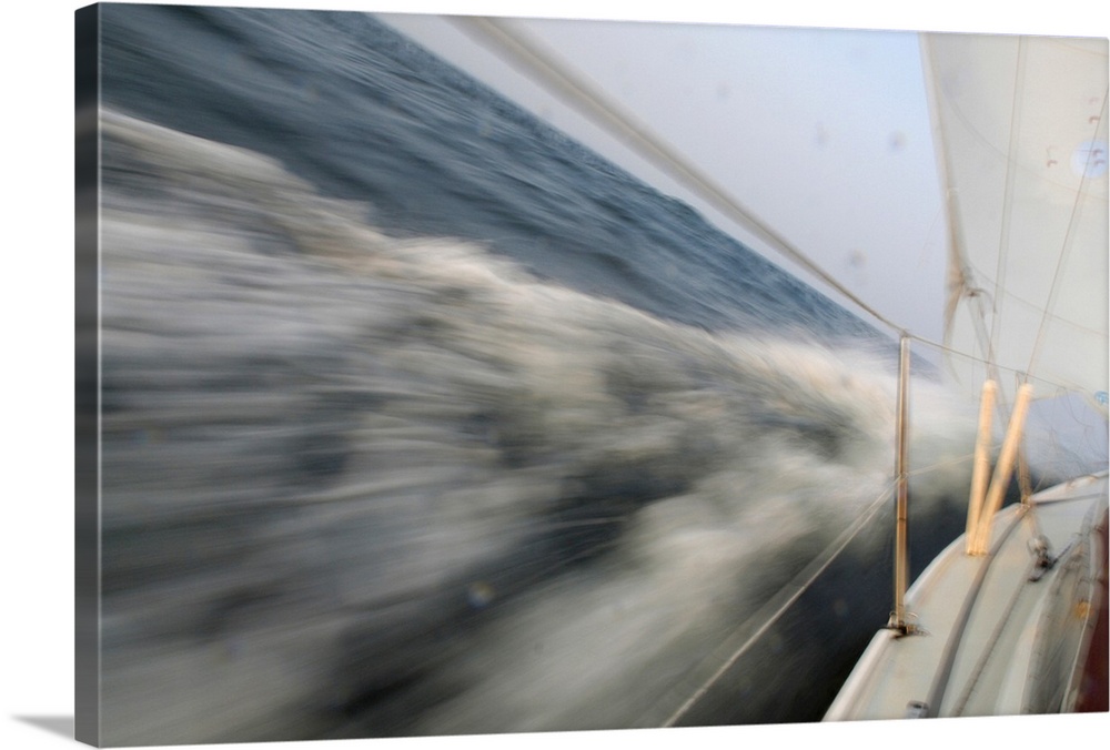 Action photo from the deck of a sailboat leaning into the ocean as it makes a sharp, fast turn.