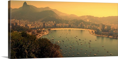 Boats floating on sea in front of Rio de Janeiro cityscape.