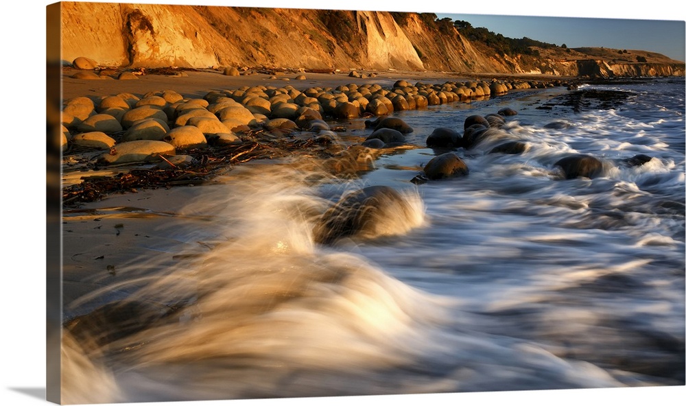 Warm sunset light paints wave splash and large round rocks at zero tide, Bowling Ball Beach, Northern California Coast, Ca...