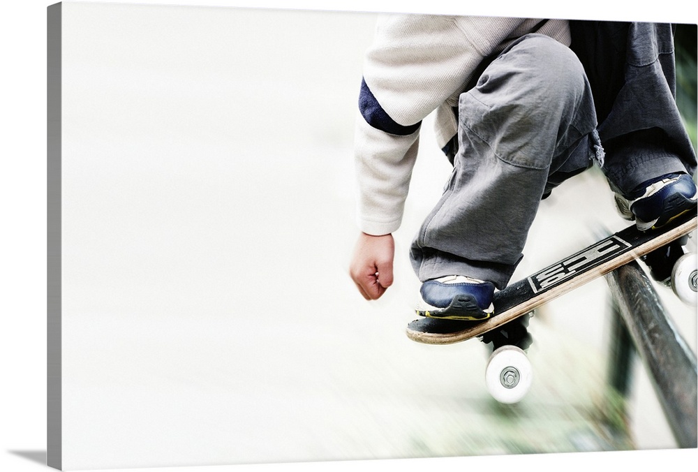 Boy (6-8) riding metal rail with skateboard, low section