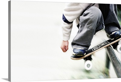 Boy riding metal rail with skateboard, low section