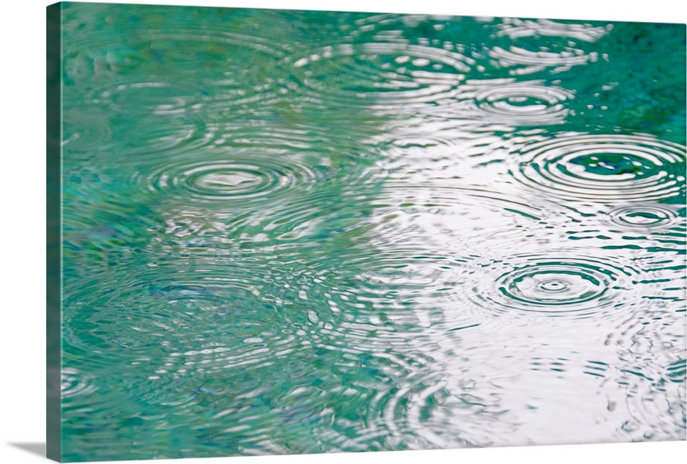 A photograph is taken of ripples in water as rain hits it.