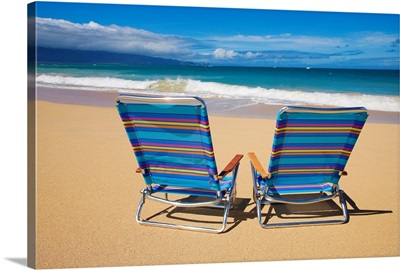 Brightly colored beach chairs on the sand near the ocean.