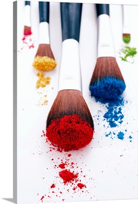 Brightly coloured eyeshadow powders on eyeshadow brushes, close-up