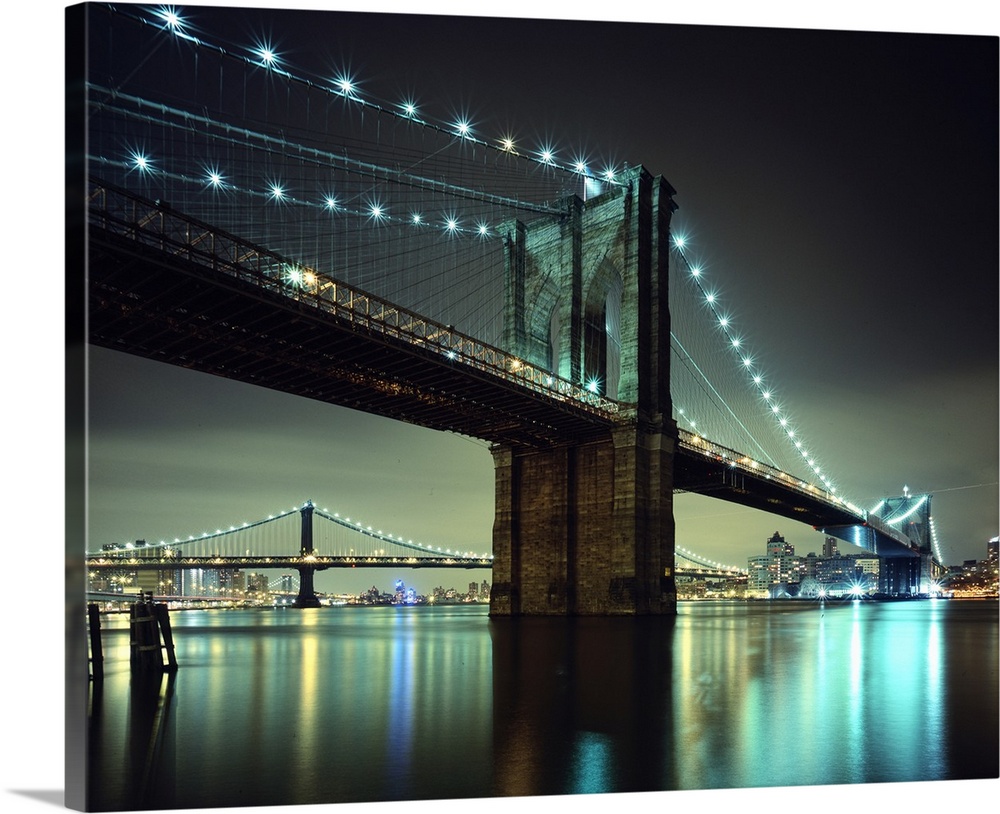 Horizontal photograph on a large wall hanging of the Brooklyn Bridge at night, the  Manhattan Bridge and Brooklyn in the b...