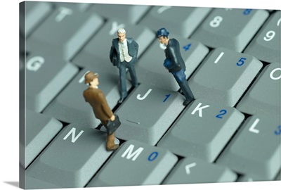 Businessmen figurines standing on a computer keyboard