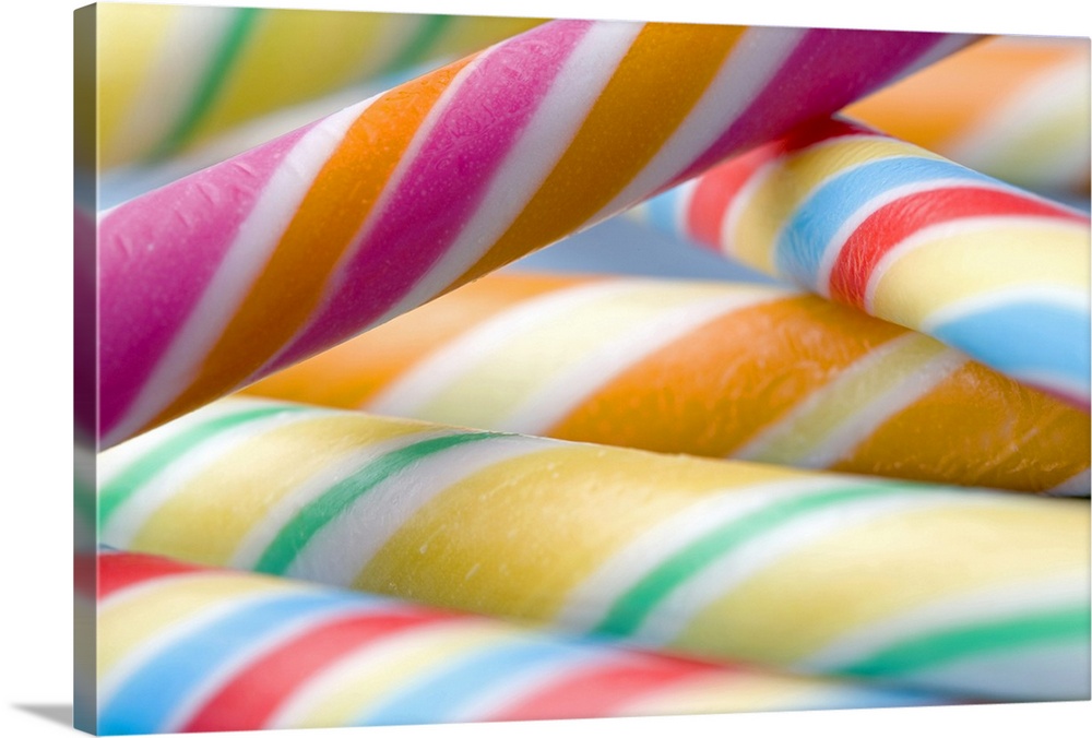 Landscape, large, close up photograph of multi-colored candy sticks, stacked in a small pile.