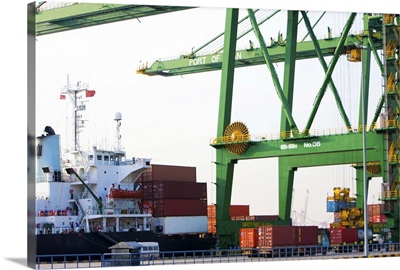 Cargo ship with cranes and cargo containers in shipping port