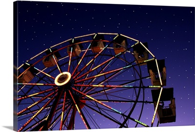 Carnival ferris wheel against starry night sky.